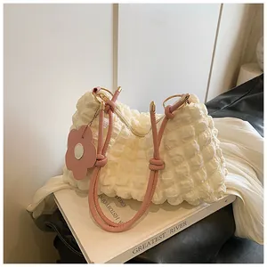 Détail du sac crème à texture gaufrée avec poignée en corde rose et breloque fleurie