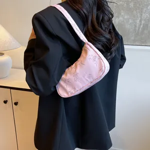 Detail of pink shoulder bag with bamboo print worn over a black blazer for high contrast