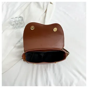 Inside view of brown leather saddle bag with magnetic closure and striped wide strap