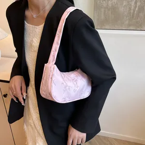 Detail of pink satin shoulder bag with bamboo leaf pattern worn by a model in a minimal setting