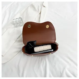Interior view of brown saddle bag showing capacity for phone, wallet, and sunglasses