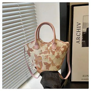 Detail showing elegant floral embroidery and pink handle on a chic trapezoid crossbody bag