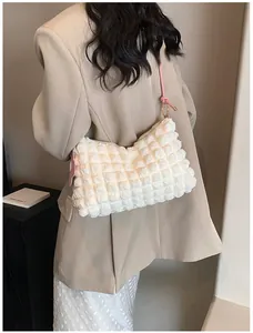 Détail du sac à texture bulles 3D avec bandoulière à nœud rose porté à l'épaule