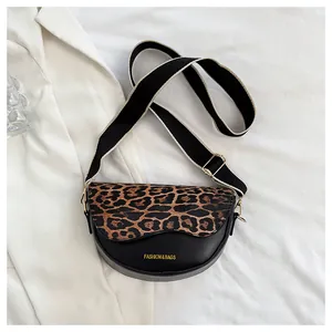 Detail of leopard print flap saddle bag with black body and wide canvas shoulder strap