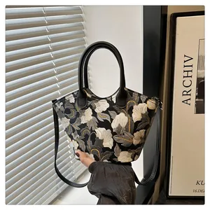 Detail of floral embroidery on a vintage crossbody bag with black leather handles