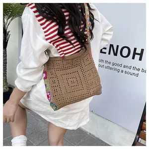 Détail d'un sac à bandoulière en tricot marron avec motifs floraux colorés au crochet