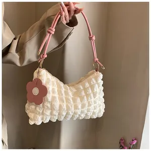 Détail de la texture bulle blanche et du charme fleur rose sur le sac cylindrique