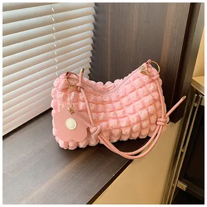 Détail du tissu à texture bulle rose sur le sac sous l'aisselle avec breloque fleur