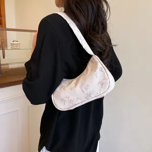 Chic crescent shoulder bag with bamboo leaf print styled on a black blazer