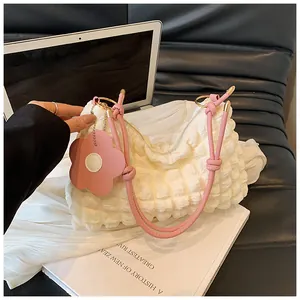 Vue détaillée du sac matelassé blanc avec poignée en cuir rose et breloque florale