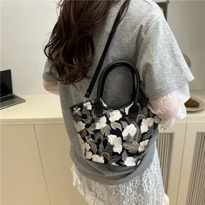 Floral embroidered handbag with black leather handles and crossbody strap in retro style