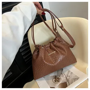 Détails de la texture en cuir tressé d'un sac seau marron avec logo Summer doré