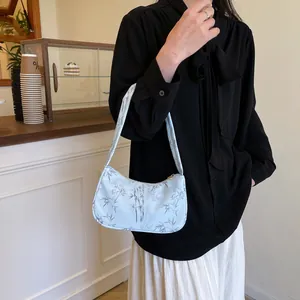 Detail of light blue hobo bag with bamboo print worn on shoulder in a cafe setting
