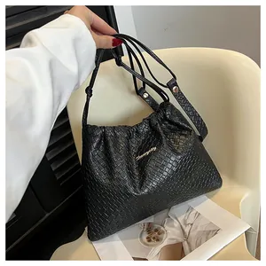 Détail du sac seau tressé noir avec fermeture à cordon et logo métallique doré