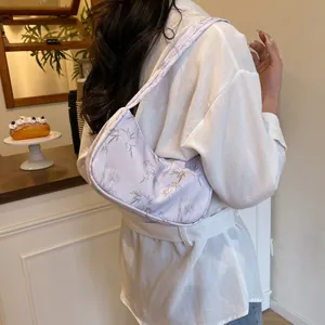 Detail of light purple hobo bag with grey bamboo leaf print worn on a female shoulder