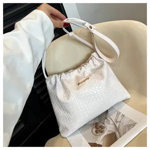 Détail du sac seau tressé blanc avec fermeture à cordon et logo métallique doré chic