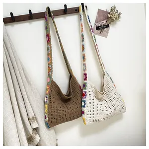 Détail de sacs fourre-tout au crochet faits main avec motifs floraux sur mur blanc