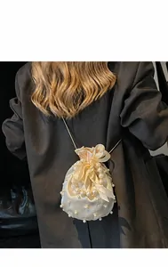 Detail der cremefarbenen Beuteltasche mit Perlenverzierung und eleganter Satinschleife