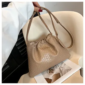 Détail de la texture tressée et lettrage doré sur ce sac seau marron à cordon coulissant