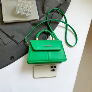 Green woven handle square handbag with gold buckle and shoulder strap on grey blazer