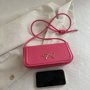 Pink faux leather shoulder bag with gold bow ornament and knotted strap detail