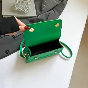 Green textured crossbody bag with magnetic flap and spacious interior on a stylish desk