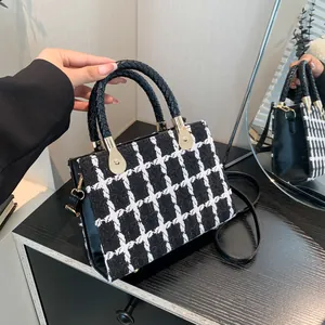 Classic checkered tweed handbag with black leather handles and elegant gold metal accents