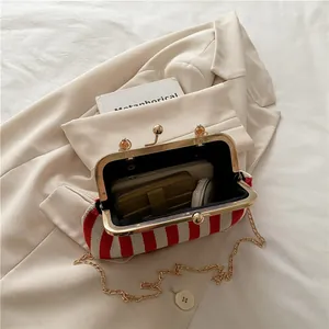 Vintage red and white striped frame handbag with gold chain on a beige blazer