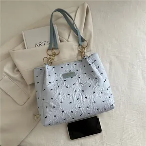 Blue tote bag with bow embroidery, pleated texture, and elegant gold chain shoulder strap