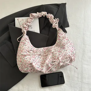 Floral pleated hobo bag with bow details and cloud strap on white textured background