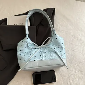 Sac à bandoulière bleu clair avec nœud et texture plissée sur fond de blazer élégant
