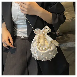Detailansicht der cremefarbenen Satin-Beuteltasche mit Perlen und Goldkette