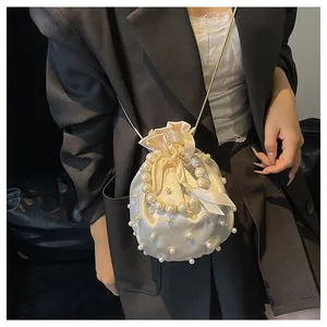 Detail der beigen Satin-Beuteltasche mit Kunstperlenverzierung und goldener Kette