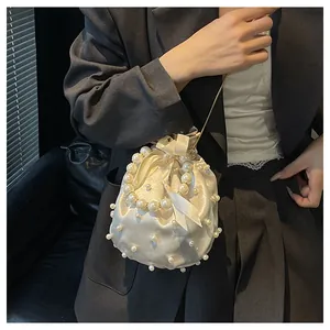 Detail der weißen Satin-Beuteltasche mit Kunstperlen-Verzierung und eleganter Schleife