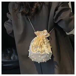Detail der elfenbeinfarbenen Satin-Beuteltasche mit Perlenverzierung und Goldkette