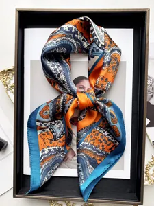 Dettaglio sciarpa di seta con motivo paisley arancione e pois a forma di fiocco