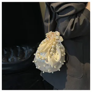 Nahaufnahme der elfenbeinfarbenen Satin-Beuteltasche mit Perlen und Seidenschleife