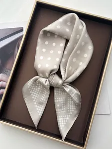 Macro detail of silk-like champagne scarf with white polka dots in a brown gift box