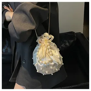 Detail der cremefarbenen Satin-Beuteltasche mit Perlenverzierung und Seidenschleife