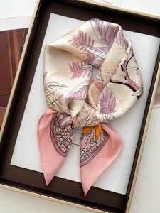 Dettaglio di sciarpa in seta rosa floreale in una scatola regalo marrone