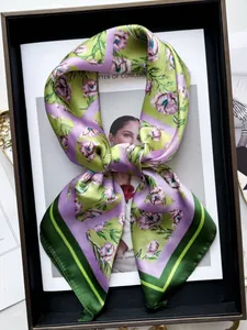 Dettaglio di un foulard in seta bicolore verde e lilla con motivi floreali eleganti