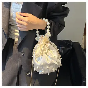 Detail der Satin-Beuteltasche mit Perlengriff und Schleifenverschluss am Model