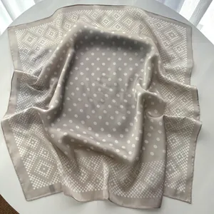 Detailed view of square silk scarf with champagne polka dots and geometric diamond patterns
