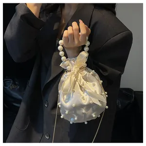 Detailansicht der elfenbeinfarbenen Satin-Beuteltasche mit Perlen, Kordelzug und Kette