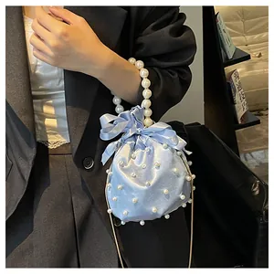 Detail der hellblauen Satin-Beuteltasche mit Perlengriff und eleganter Schleife