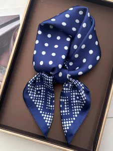 Detail shot of navy blue polka dot silk scarf tied in a bow inside a premium display box