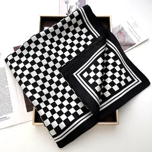 Close-up of black and white checkered silk scarf displayed in an elegant gold frame box