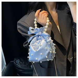 Detail der hellblauen Satin-Beuteltasche mit Perlenverzierung und einer Schleife