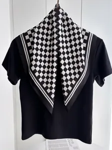 Detail of silk-like square scarf with black and white checkerboard pattern on a black tee