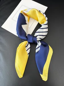 Close-up of silk-feel square scarf with yellow and navy blue geometric block patterns